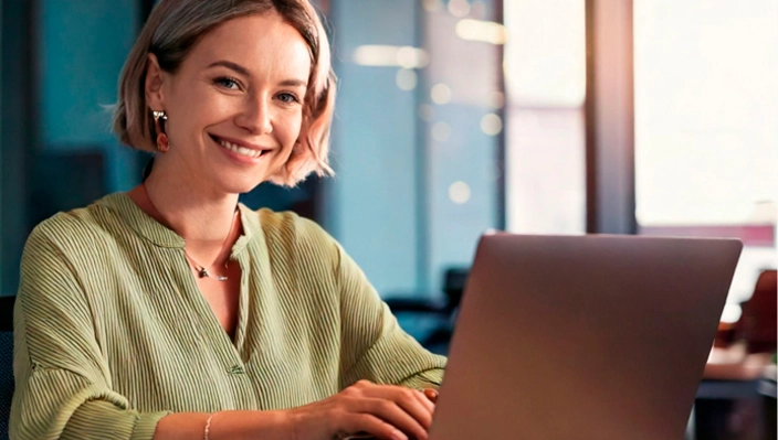 Profissional sorrindo enquanto usa um notebook
